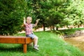 Smiling happy boy sitting on bench near lake. Summer time weekend mood. Royalty Free Stock Photo