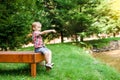 Smiling happy boy sitting on bench near lake. Summer time weekend mood. Royalty Free Stock Photo