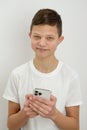 smiling happy boy 12 years old wearing white t-shirt hold in hand use mobile cell phone isolated on plain white Royalty Free Stock Photo