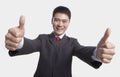 Smiling happy businessman giving thumbs-up with both hands to the camera, studio shot Royalty Free Stock Photo