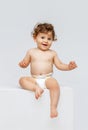 Vertical portrait of little cute toddler boy, baby in diaper joyfully sitting and laughing isolated over white studio Royalty Free Stock Photo