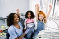 Smiling happy children, two multiracial girls, visiting dentist, sitting in dental chair, gesturing success with arms up Royalty Free Stock Photo