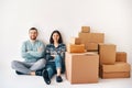 Smiling happy couple sitting on floor after the moving to new house with cardboard boxes Royalty Free Stock Photo