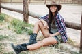 Smiling happy cowgirl sitting and resting at the ranch fence Royalty Free Stock Photo