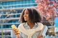 Happy cute African girl student walking in university park holding mobile phone. Royalty Free Stock Photo