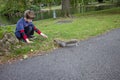 Boy by lake in Boston public garden reaching out to squirrel