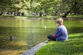 Boy sitting by lake in Boston public garden with a duck Royalty Free Stock Photo