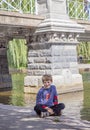 Boy sitting by lake in Boston public garden by bridge Royalty Free Stock Photo