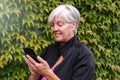 Smiling happy elderly woman talking outside on a mobile phone with nice autumn leaves Royalty Free Stock Photo