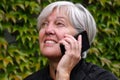 Smiling happy elderly woman talking outside on a mobile phone with nice autumn leaves Royalty Free Stock Photo