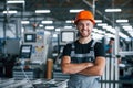 Smiling and happy employee. Industrial worker indoors in factory. Young technician with orange hard hat