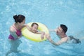 Smiling happy family playing in the pool with their son in an inflatable tube Royalty Free Stock Photo