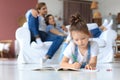 Smiling happy family sit relax on couch in living room watch little daughter drawing in album with colorful pencils