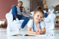 Smiling happy family sit relax on couch in living room watch little daughter drawing in album with colorful pencils