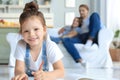 Smiling happy family sit relax on couch in living room watch little daughter drawing in album with colorful pencils