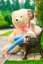 Smiling happy girl on a bench with your favorite teddy bear in t