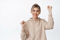 Smiling happy girl raising hands to support or endorse someone, rooting for team, cheering for you, standing over white