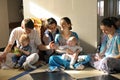 Smiling and happy Hare Krishna adults and babies family sitting on the floor, talking in the temple