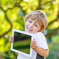 Smiling happy little child holding tablet pc, outdoors Royalty Free Stock Photo