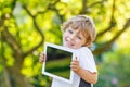 Smiling happy little child holding tablet pc, outdoors Royalty Free Stock Photo