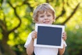 Smiling happy little child holding tablet pc, outdoors Royalty Free Stock Photo