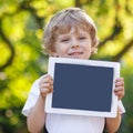 Smiling happy little child holding tablet pc, outdoors Royalty Free Stock Photo