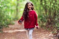 Smiling happy little girl and autumn big pinecone in hands enjoying fall in wild color autumnal forest