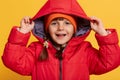 Smiling happy little girl wearing red jacket and orange cap, happy female child with dark hair and pigtails, wearing hood, looking Royalty Free Stock Photo