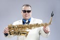 Smiling Happy Male Saxo Player in White Suit and Sunglasses Posing with Saxophone Against White Background Royalty Free Stock Photo