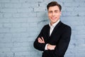 Smiling happy man in black suit with crosed hands