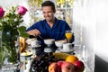 Happy smiling man in his pijamas having breakfast at table in front of patio doors with view of garden. Royalty Free Stock Photo