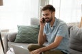 Smiling happy man using laptop and talking on phone at home Royalty Free Stock Photo