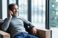 Smiling happy mature asian man with white stylish short beard using smartphone tablet talking at coffee shop cafe