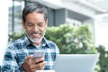 Smiling happy mature man with white stylish short beard using smartphone gadget serving internet at coffee shop cafe outdoor Royalty Free Stock Photo