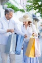 Happy mid adult married couple returning from shopping and carrying colorful bags