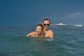 Smiling happy mother and son playing on the wave in the sea in the daytime. Happy family relaxing by the sea. Summer, spring and w Royalty Free Stock Photo