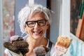 Smiling happy older woman portrait, proud artist, in her fifties with grey hair and black glasses and many paintbrushes Royalty Free Stock Photo