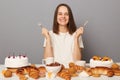 Smiling happy optimistic woman wearing white T-shirt eating with good appetite delicious desserts, isolated over gray background, Royalty Free Stock Photo