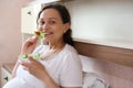 Smiling happy positive pregnant woman eats a healthy salad with fresh raw vegetables and herbs, looking at camera Royalty Free Stock Photo
