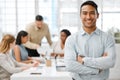 Smiling, happy and proud young business man with arms crossed showing great leadership to his team in an office Royalty Free Stock Photo