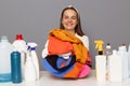 Smiling happy satified woman posing at workplace with cleaning detergents isolated over gray background doing laundry being happy