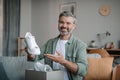 Smiling happy senior european man blogger with beard records video review on shoes, unpacks box with purchases Royalty Free Stock Photo
