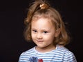 Smiling happy  small kid girl with grimacing face looking and deciding the question on black studio background. Closeup Royalty Free Stock Photo