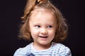 Smiling happy  small kid girl with grimacing face looking and deciding the question on black studio background. Closeup Royalty Free Stock Photo