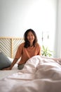 Smiling asian girl sitting on bed after waking up in the morning at home looking at camera. Vertical. Copy space. Royalty Free Stock Photo