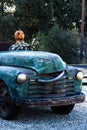 Smiling, happy, welcoming, fun friendly pumpkin head scarecrow driving an old truck to a halloween harvest party