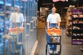 Smiling happy woman enjoying shopping at the supermarket, she is leaning on a full cart Royalty Free Stock Photo