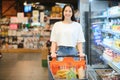 Smiling happy woman enjoying shopping at the supermarket, she is leaning on a full cart Royalty Free Stock Photo