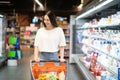 Smiling happy woman enjoying shopping at the supermarket, she is leaning on a full cart Royalty Free Stock Photo