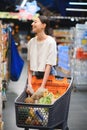 Smiling happy woman enjoying shopping at the supermarket, she is leaning on a full cart Royalty Free Stock Photo